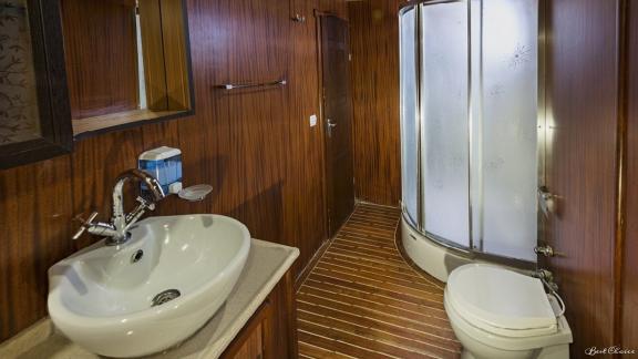 Modernes Badezimmer mit geräumiger Dusche, stilvollem Waschbecken und eleganter Holzverkleidung.